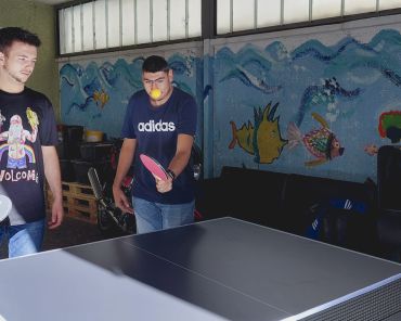 zwei junge Männer spielen im Team Tischtennis; die gegnerische Mannschaft ist nicht sichtbar