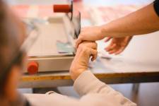 Ein Klient und eine unterstützende Person bedienen gemeinsam einen Hebelschneider. 