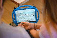 Zwei Personen, ein Klient und eine Unterstützerin, schauen sich ein Tablett mit Metacom Symbolen an. 