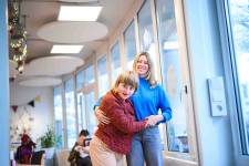 Eine Frau mit rotem Hemd stützt sich auf eine Frau mit blauem Hemd.