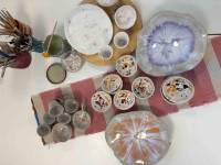 Mehrere bunte Keramikteller und Keramiktassen von oben auf ein Tisch mit kurzem bunten Tischläufer. 