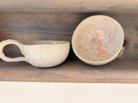 Eine Keramiktasse mit Griff und eine Keramikschüssel stehen nebeneinander im Regal. 