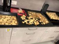 Vier Backbleche voller Kekse, nebeneinander abgelegt auf der Küchentheke.