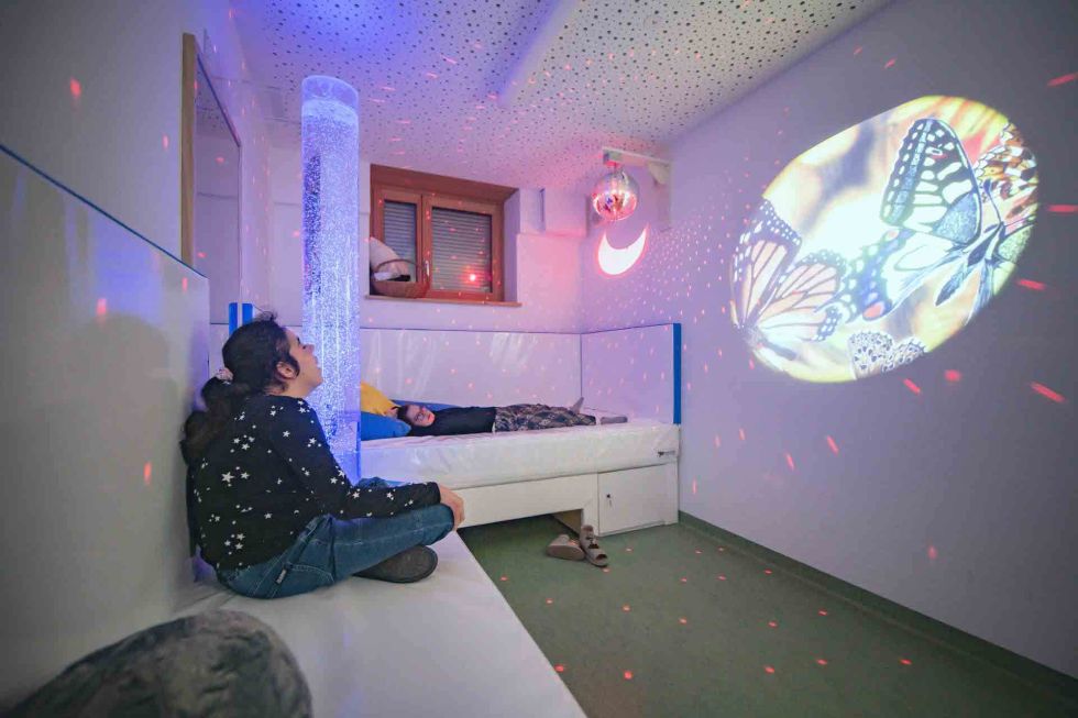 zwei junge Frauen entspannen in Betten und betrachten eine Projektion an die Wand