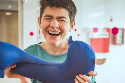 Eine Frau hält einen Nackenpolster und lacht