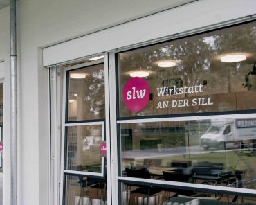 eine Fensterscheibe mit einer Beklebung: das slw Logo und "Wirkstatt an der Sill"