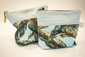 zwei Kulturbeutel mit einem Stoff auf dem Palmen sind