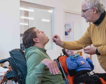 ein Mann im Rollstuhl erhält eine Hostie von einem anderen Mann
