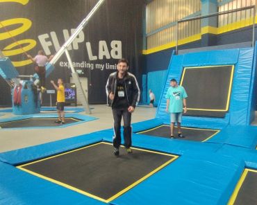 viele Trampoline in einer Halle; in der Mitte steht ein Mann