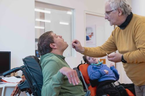 ein Mann im Rollstuhl erhält eine Hostie von einem anderen Mann