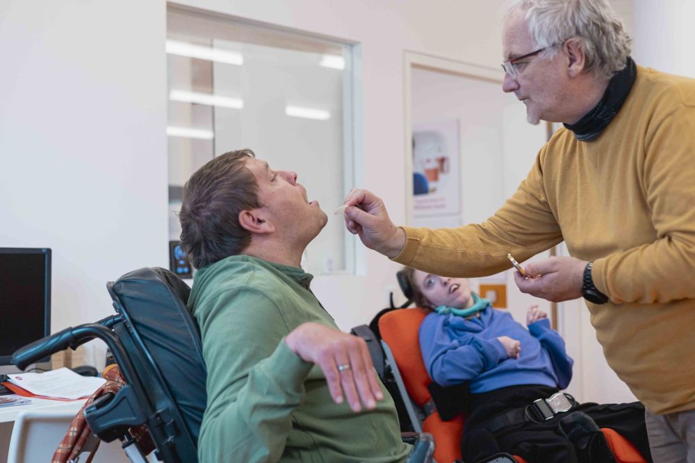 ein Mann im Rollstuhl erhält eine Hostie von einem anderen Mann