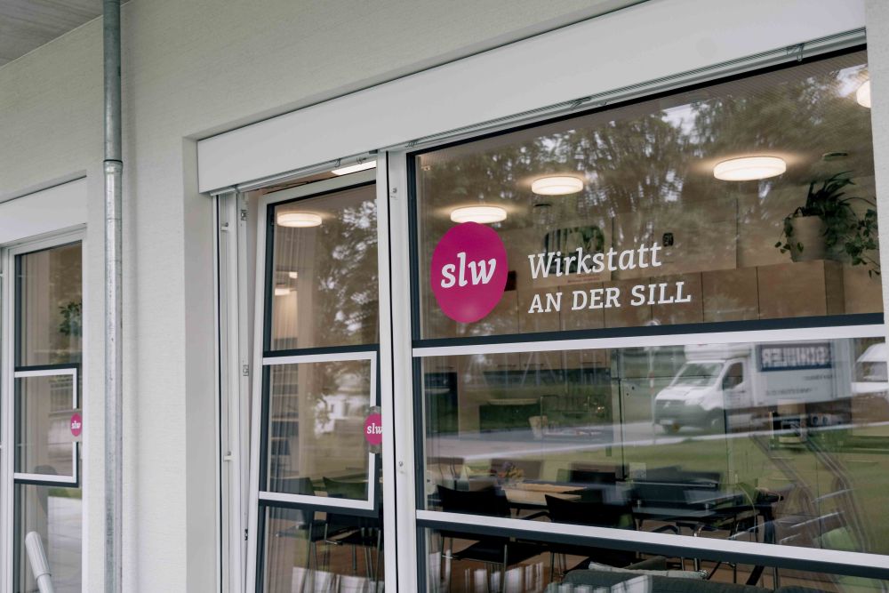 eine Fensterscheibe mit einer Beklebung: das slw Logo und "Wirkstatt an der Sill"