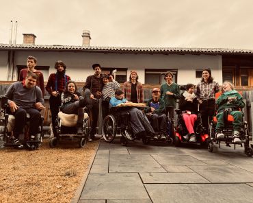 ein Gruppenbild von mehreren Erwachsenen mit Behinderungen und ihren Unterstützer_innen; einige sitzen im Rollstuhl; Aufnahme im Freien