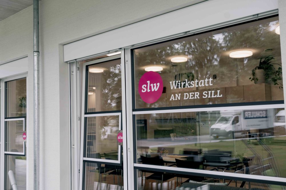 eine Fensterscheibe mit einer Beklebung: das slw Logo und "Wirkstatt an der Sill"