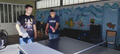 zwei junge Männer spielen im Team Tischtennis; die gegnerische Mannschaft ist nicht sichtbar