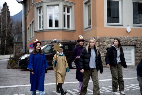 drei Sternsinger spazieren mit zwei Begleitpersonen über einen Parkplatz